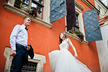 Wedding couple near orange house with windows