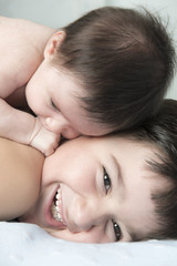 Obraz na płótnie Canvas Niño jugando con su hermano bebé con un gesto de felicidad en sus caras