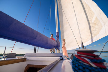 Fototapeta premium Elegant dressed couple riding on a yacht
