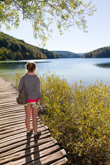 Woman walking on the wooden footpath near a lake in national park Plitvice in Croatia in autumn