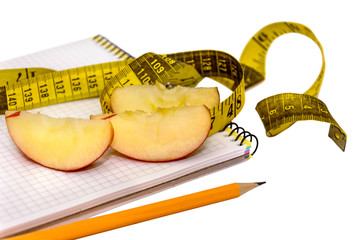 Apple, pencil and measuring tape on notepad isolated on white