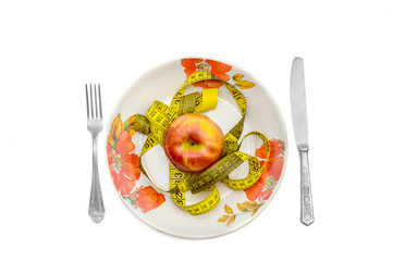 Tape measure and apple on plate with knife and fork. isolated on