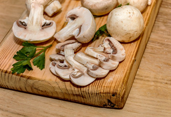 Sliced mushroom lies on a kitchen wooden board
