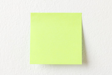 Yellow note pad on white wall background