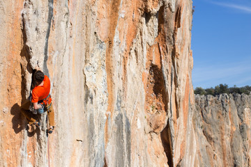 Young man climbing on a limestone wall with wide valley on the background