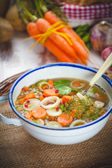 Vegetable soup in a metal bowl on a rural rustic wooden table.