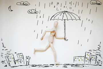 Man running home under umbrella in raining. Abstract image with wooden puppet