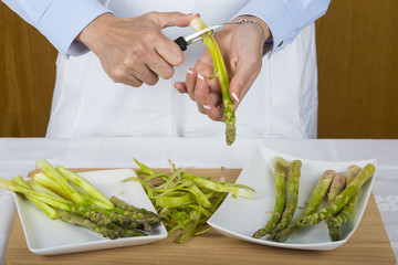 Cocinero pelando y preparando espárragos para cocinar