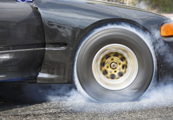 Drag racing car burns rubber off its tires in preparation for th