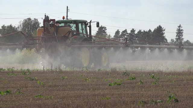 Back of vehicle spreading fertilizer on a farm field of corn stubble. Agricultural plains spraying with special substance. Panorama shot. 4K
