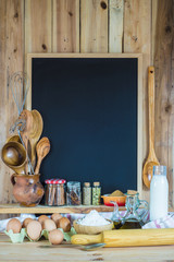 Obraz na płótnie Canvas Pizarra de fondo negro con espacio vacío para texto decorada con utensilios de cocina e ingredientes de repostería y pastelería
