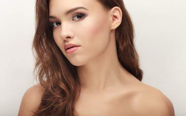 Closeup beauty portrait of young calm brunette woman with bare shoulders showing trendy  makeup on white studio background