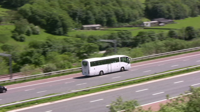 Unliveried plain white coach on the M6 motorway running on the inside lane, passing through the English countryside of Cumbria near Tebay.