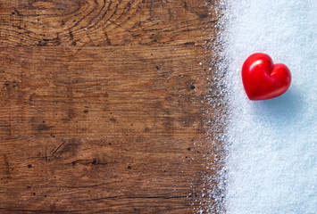 Red stone heart on white snow winter and rustic background. Love and St. Valentines Day concept.