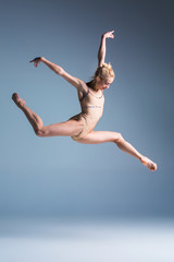 Young beautiful modern style dancer jumping on a studio background