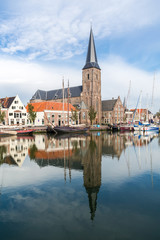 Fototapeta na wymiar Saint Michaels Church and historic houses on quay of Zuiderhaven harbour canal with boats in Harlingen, Friesland, Netherlands