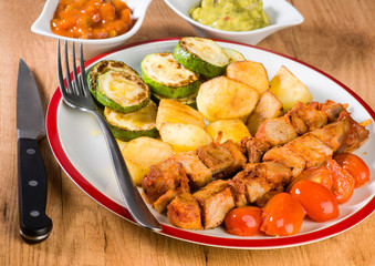 skewered meat and vegetables on wooden plate