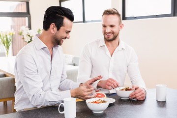 Smiling gay couple having breakfast