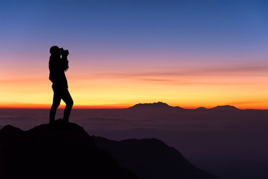 silhouette of woman taking photograph on the top of mountain and © chanwitohm