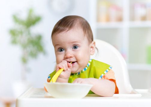 baby child sitting in chair with a spoon