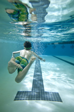 boy swimming under water in pool, view from underwater