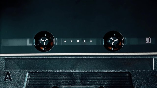 Vintage top class audio cassette spinning in the deck, clean close-up