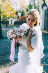 Fototapeta na wymiar Beautiful bride with wedding bouquet of flowers roses outdoors in green park