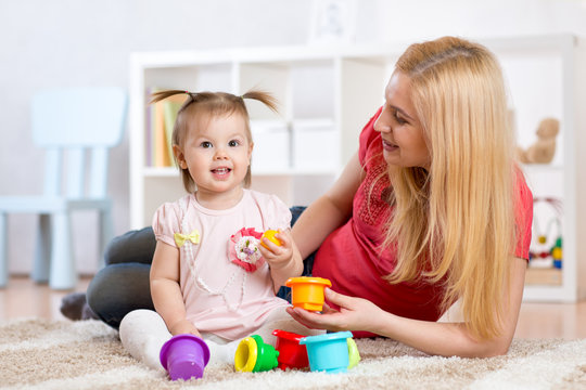 child girl and mother playing together with toys at home