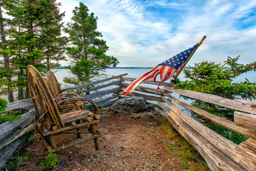 Rustic willow twig chairs and American flag overlooking ocean. Acadia, Maine - Powered by Adobe