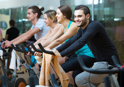 adults riding stationary bicycles in fitness club
