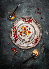 Camembert cheese served on a silver platter with berries and honey, top view