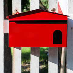 Red mailbox on white fence