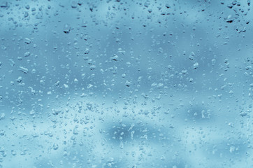 Naklejka na ściany i meble Raindrops on window glass, toned blue
