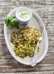 Zucchini fritters with herbs on a ceramic plate on a  wooden background. Healthy, vegetarian food