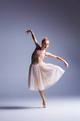 Young beautiful modern style dancer posing on a studio background