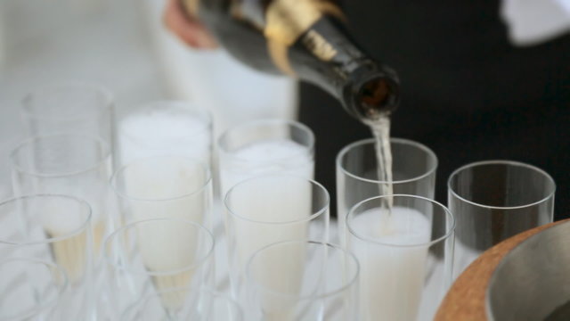 Waiter pours champagne into glasses 