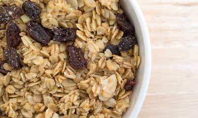 Top close view of a bowl of granola cereal on a wood table top