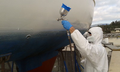 worker spray painting yacht sail boat with spray gun