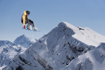 Flying snowboarder on mountains. Extreme sport.