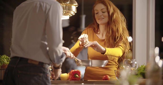Woman cut raw vegetables for dinner while man drink wine at home in the evening in slow motion (in realtime at 60 fps)