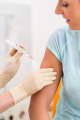Frau beim Arzt erhält Impfung per Spritze