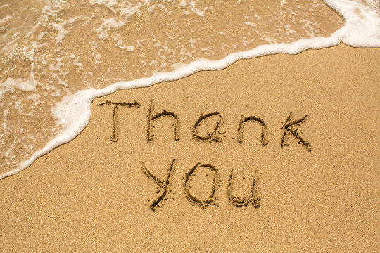 Thank you - Inscription on sand beach with the soft wave.