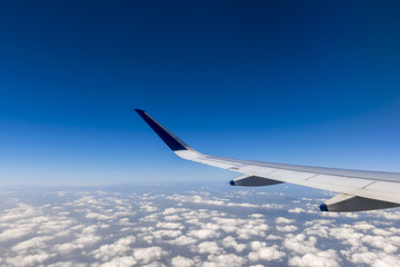 Wing of a flying passenger airplane above clouds
