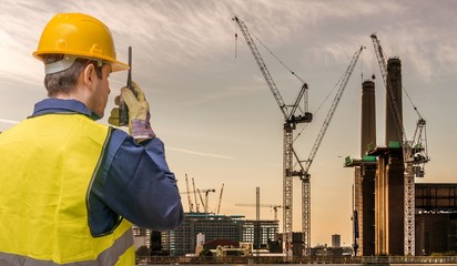Obraz na płótnie Canvas Worker is using radio and crane site. Construction concept.