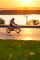 Obraz premium Child riding a bike along river