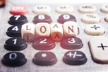Calculator with the word loan written in wooden block letters
