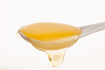 White cheramic spoon filled with sweet golden honey.