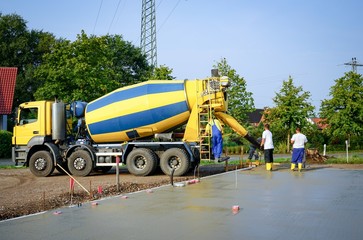 Betonmischer liefert Fertigbeton  - Bauarbeiter verteilen den Beton