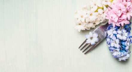 Fork with hyacinths flowers on light green background, top view, banner for website or placard.  Place setting concept. Spring or Easter food.