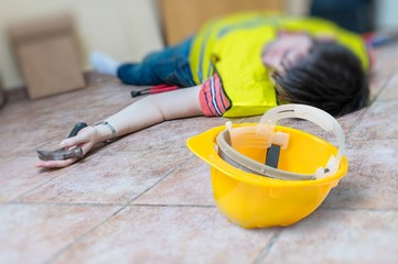 Work injury concept. Worker had an accident and is lying injured on the floor.